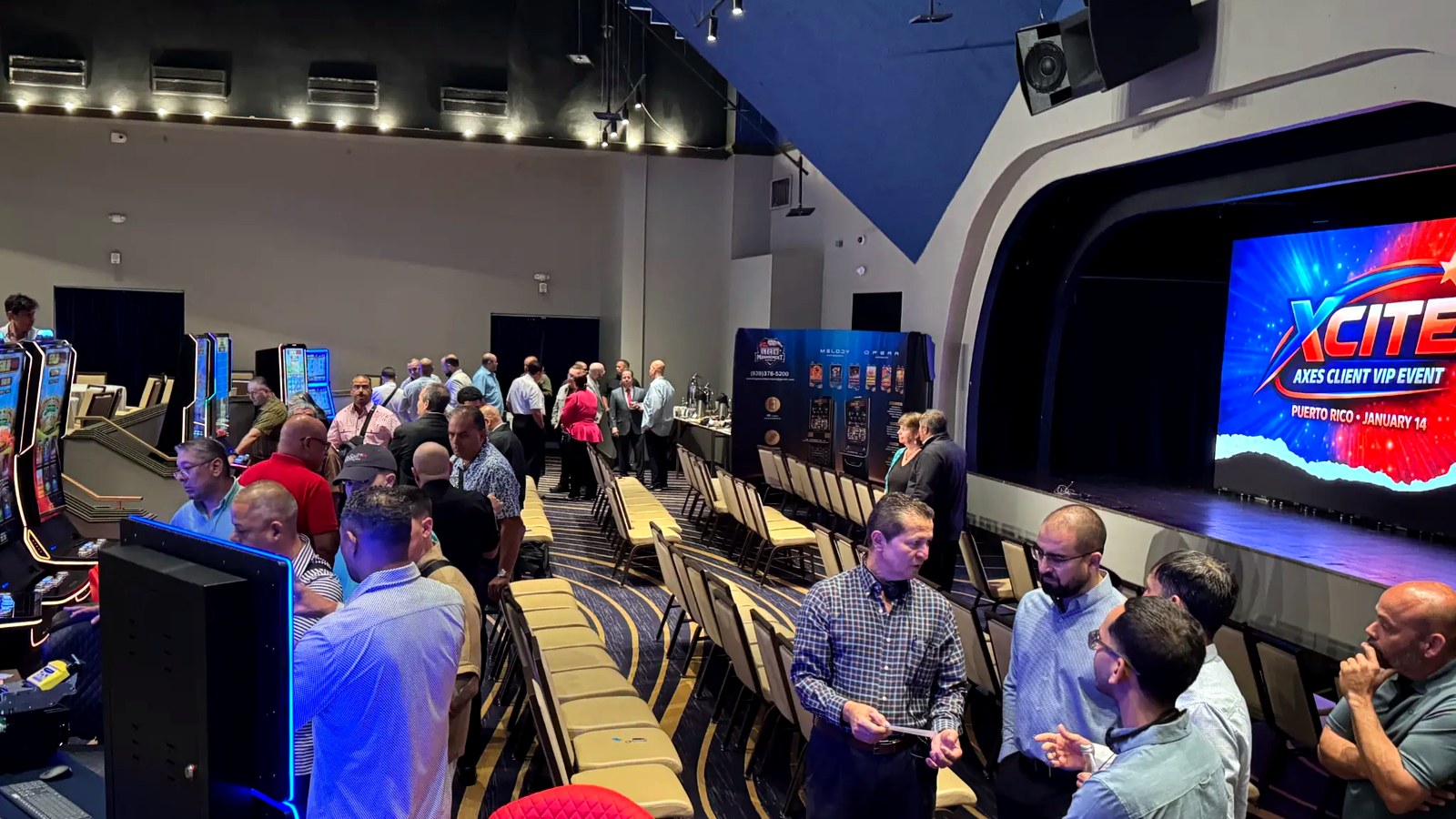 Attendees networking on the floor as the XCITE Puerto Rico branding lit up the main screen.
